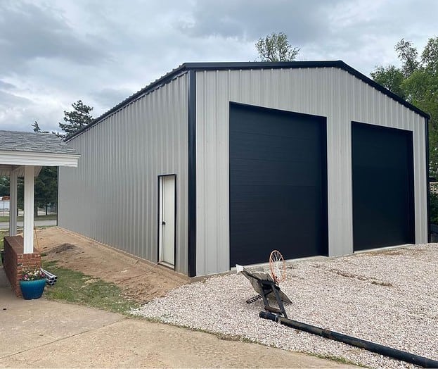 Grey Metal Building with vertical siding and black roll up doors.